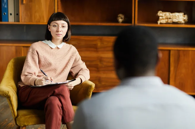 Two people in a one-to-one conversation, one taking notes